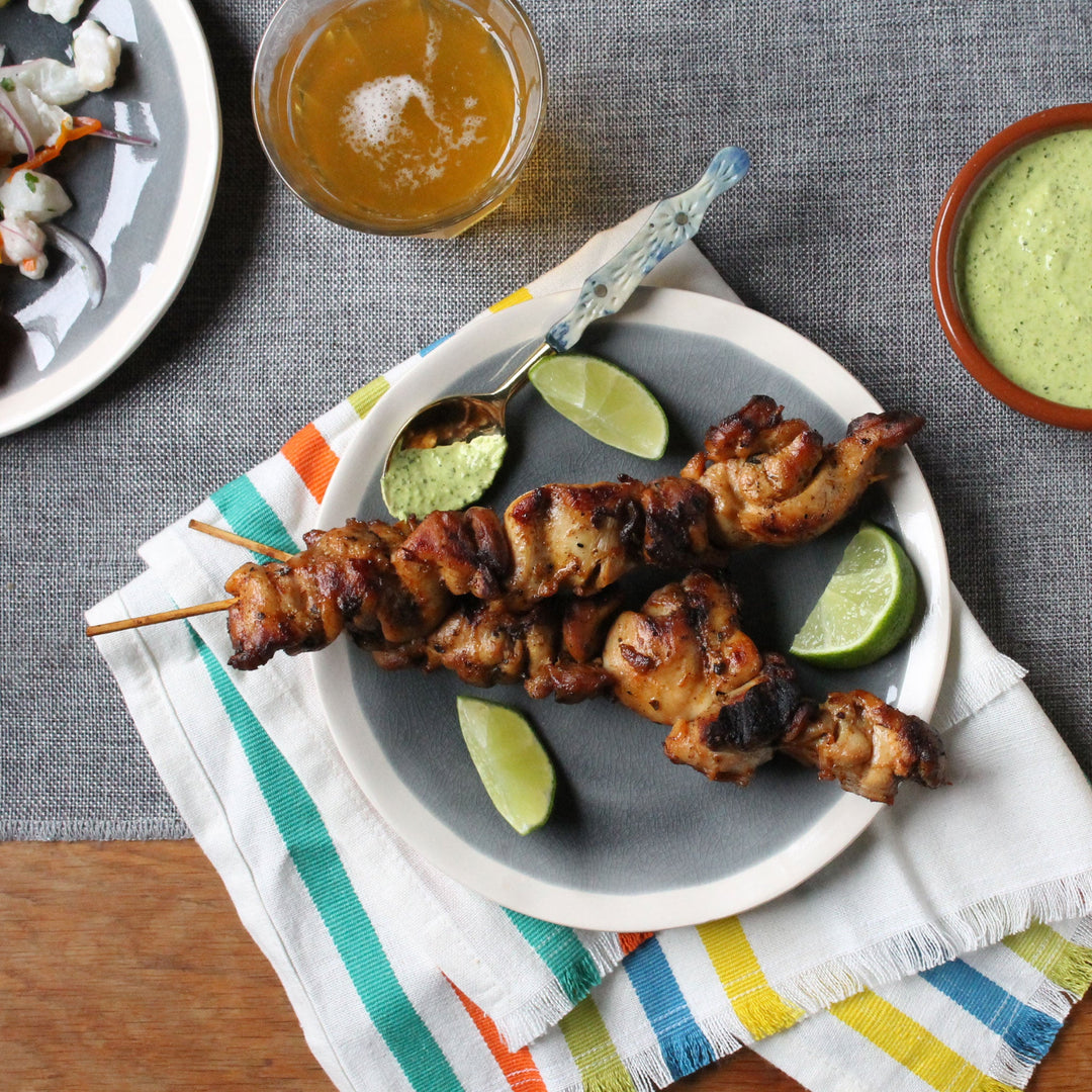 Peruvian chicken skewers with sliced limes 