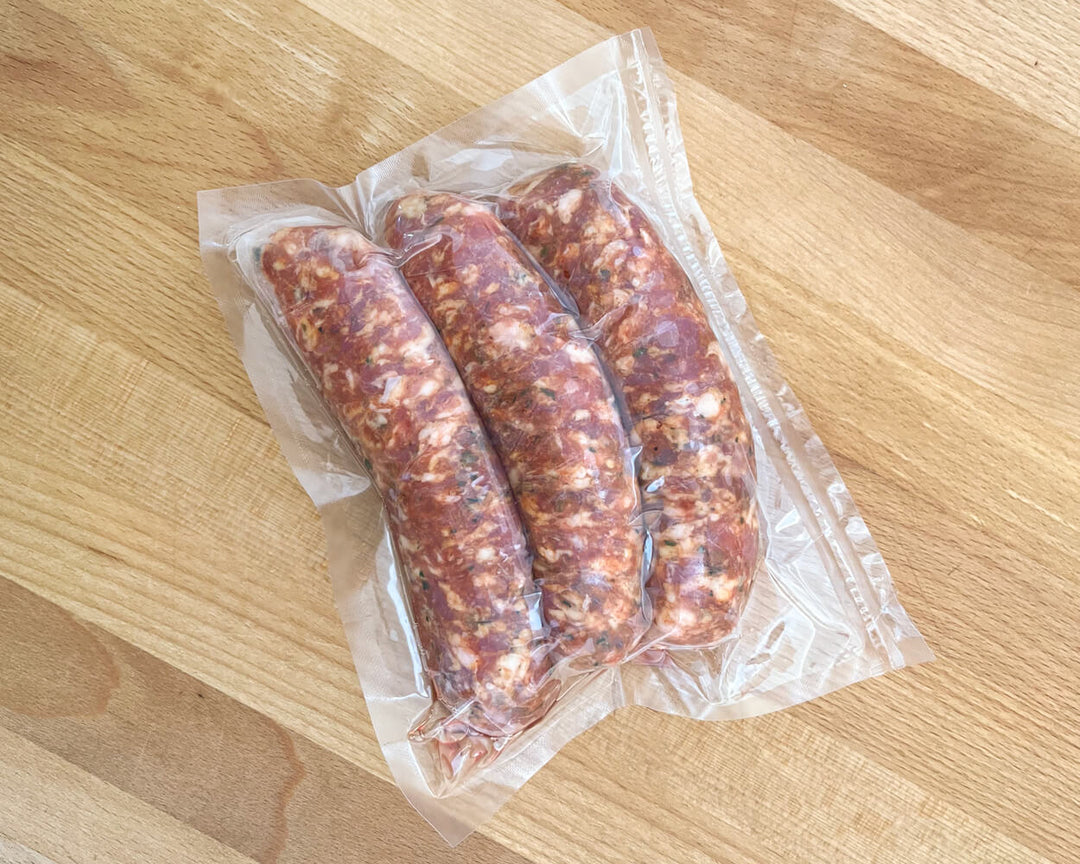 Packaged pork sausages visible through clear plastic wrapping on a wooden surface.