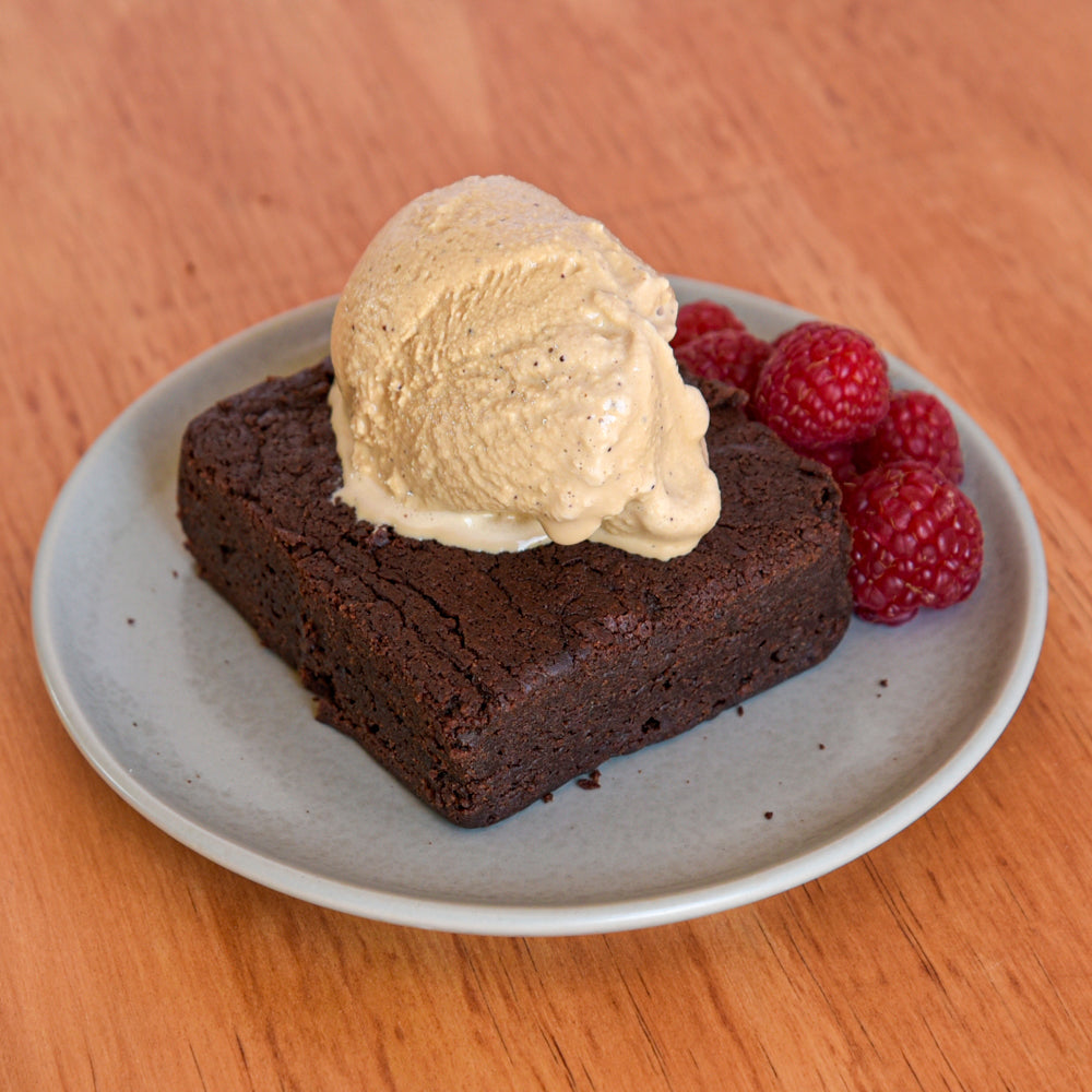 Chocolate brownie square topped with a scoop of ice cream and served with raspberries