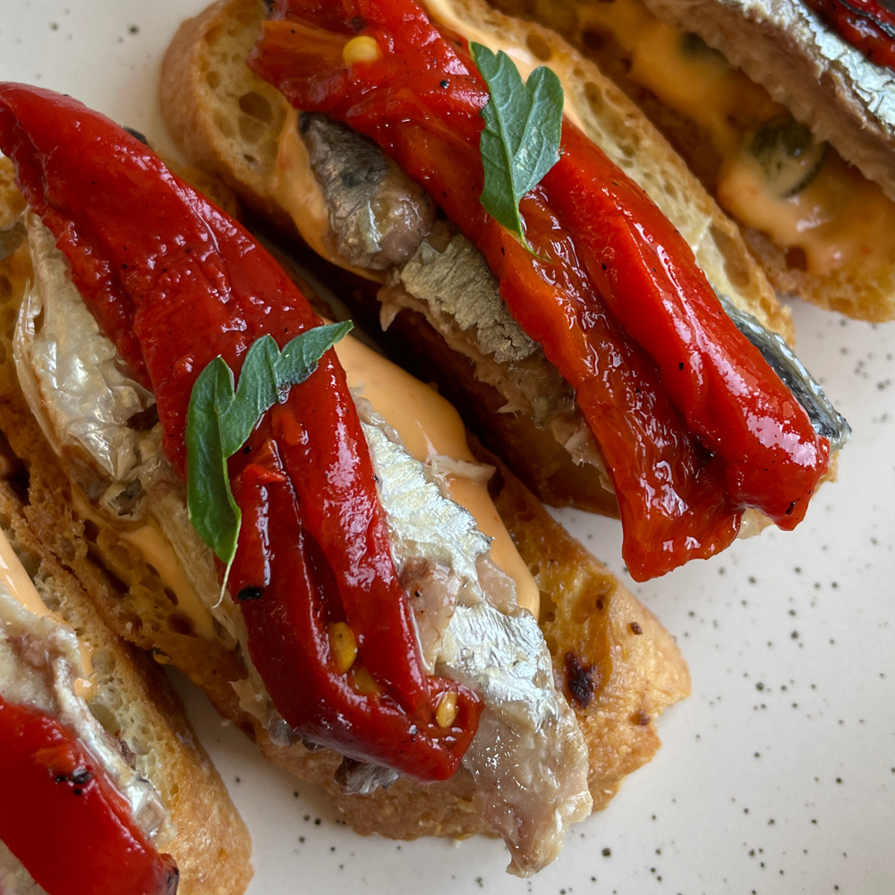 Sardines with piquillo peppers on a speckled plate
