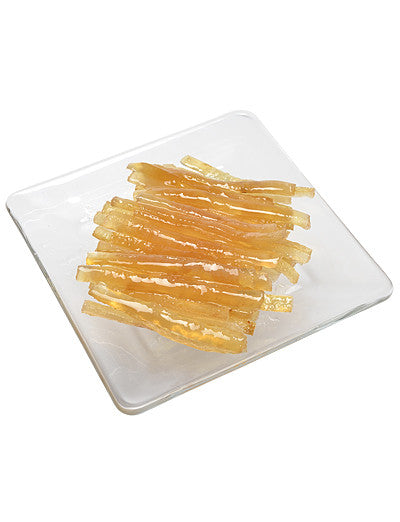 Candied lemon peel strips arranged on a clear glass plate.