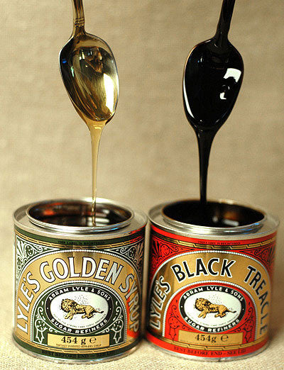 Spoons dripping over open jars of Tate and Lyle's Golden Syrup and Black Treacle